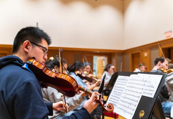 Image of student participating in orchestra rehearsal.